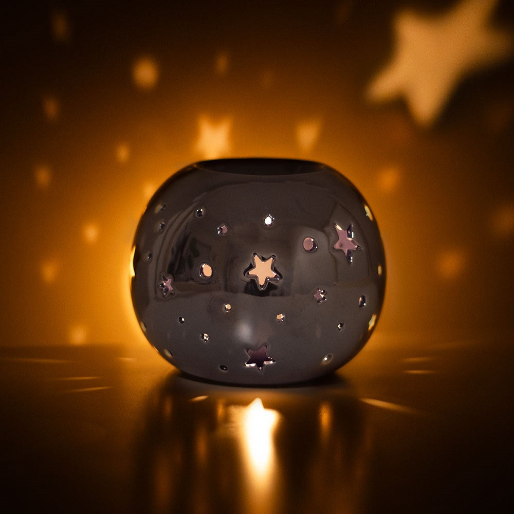 purple cut out start ceramic tealight wax burner lit and glowing warm colours
